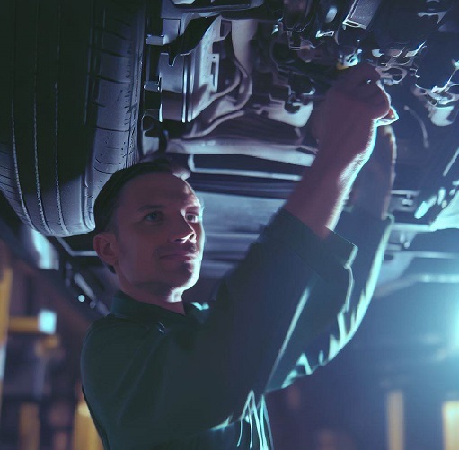 mechanic inspecting the underside of a vehicle focusing on transmission